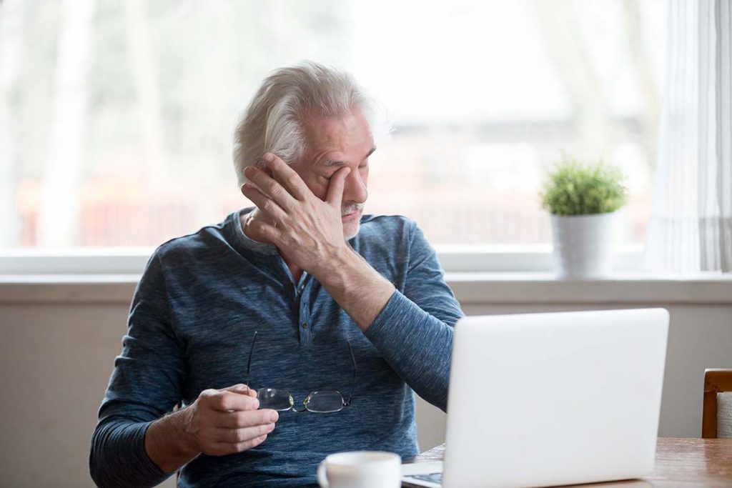 Man with dry eyes working on computer